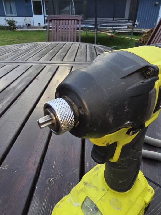 Skruvdragare på ett träbord utomhus, med en fastkilad bits i chucken.