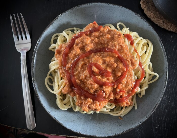Chorizofärssås med spaghetti och ketchup på en tallrik, gaffel till vänster.