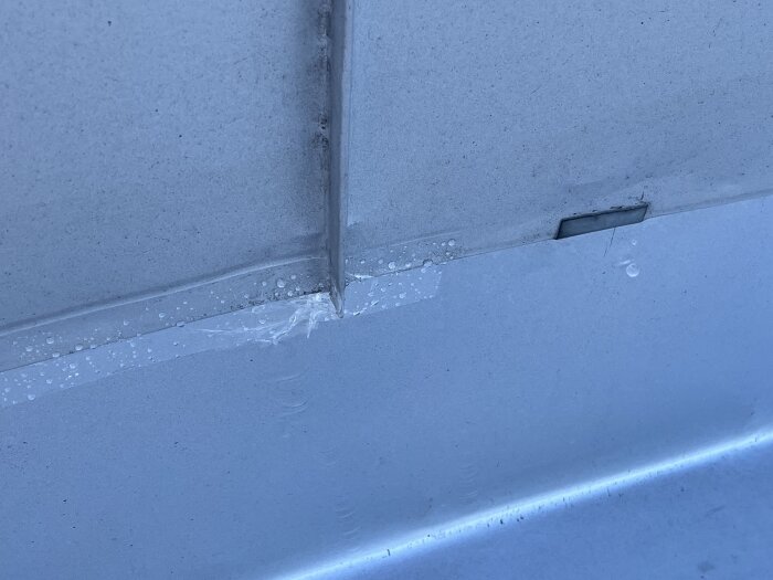 Genomskinlig tejp på tak med vattendroppar testas för läckage vid knytning mellan sektioner.