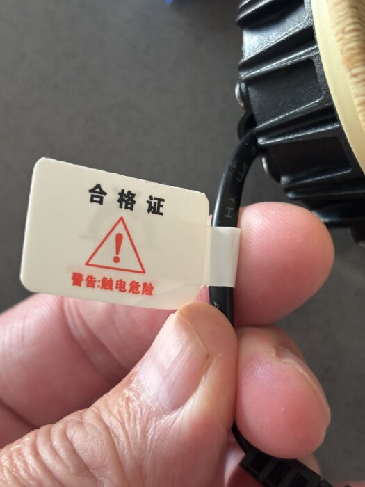 Svart kabel med varningsskylt på okänt språk.