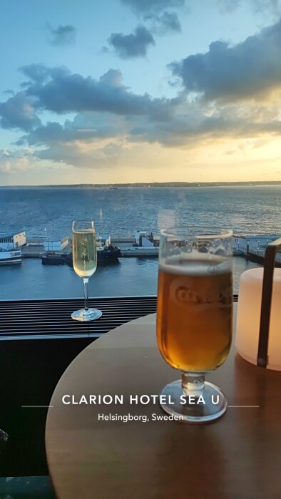 Utsikt över havet från Clarion Hotel Sea U i Helsingborg med ett glas öl och ett glas mousserande vin på ett bord.