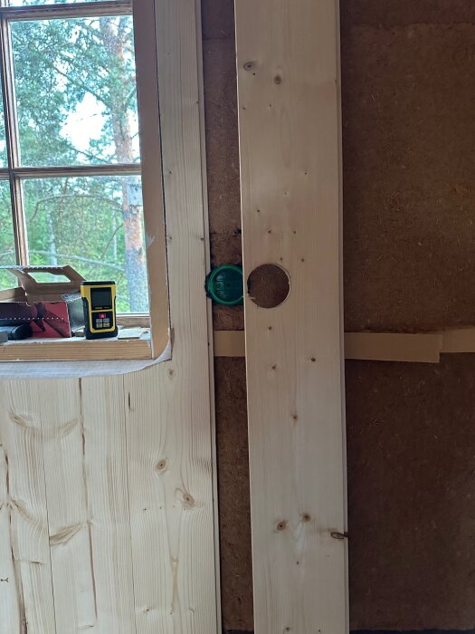 Stående träpanel med uttag för eluttag monteras bredvid fönster, verktyg och utrustning placerade intill.