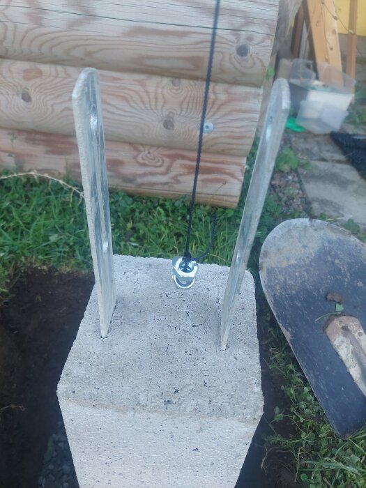 Betongplint med lodlina och plintjärn, del av altan- eller balkongstödprojekt.