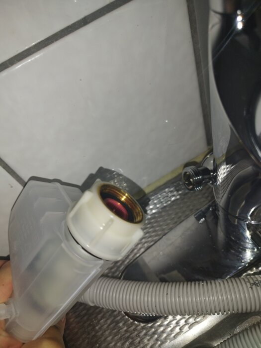 Anslutningsslang från en bänkdiskmaskin håller mot en kran, som visar att inkopplingen är för stor för koppling till kranen.