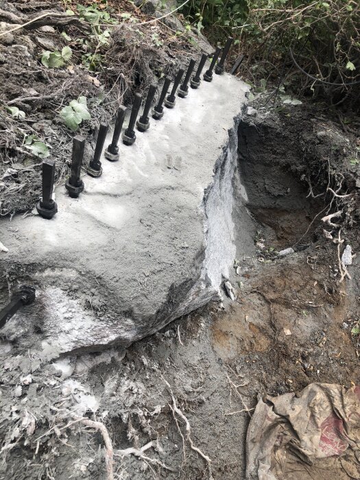 Kilar i rad på en stor sten som har delats med hjälp av brytteknik. Omkringliggande jord och rötter syns tydligt i bakgrunden.