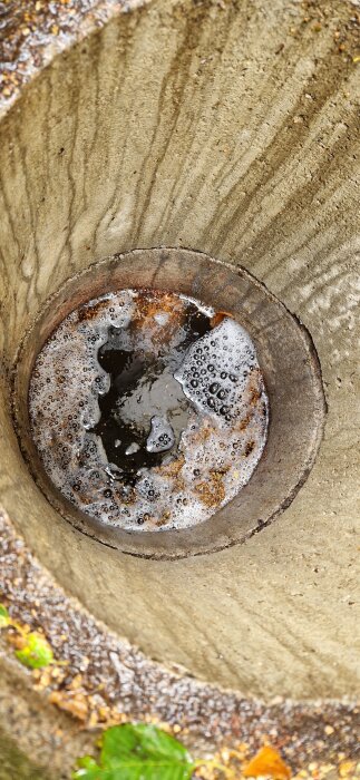 Vattensamlare med skum och bubblor inuti ett betongrör efter regn, nivå strax ovanför utloppsröret.