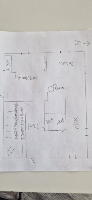 Skiss av bottenvåningen med vardagsrum, matsal, hall, kök och toa markerade samt utgångar och trappor.