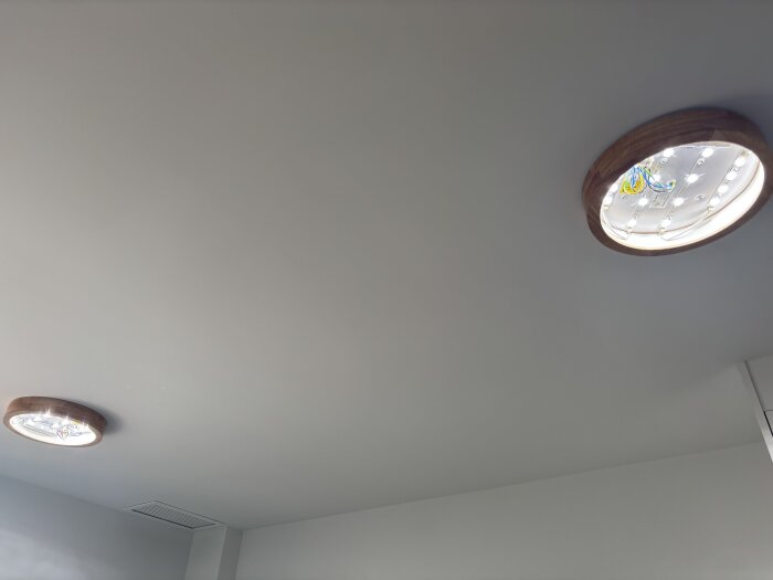 Två taklampor monterade, den ena med synliga ledningar i blått, gult och grönt.