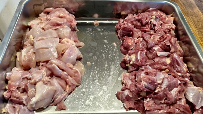 Två högar med styckat kött i en metallbricka, en ljusare och en mörkare hög, förberett för färsmalning.