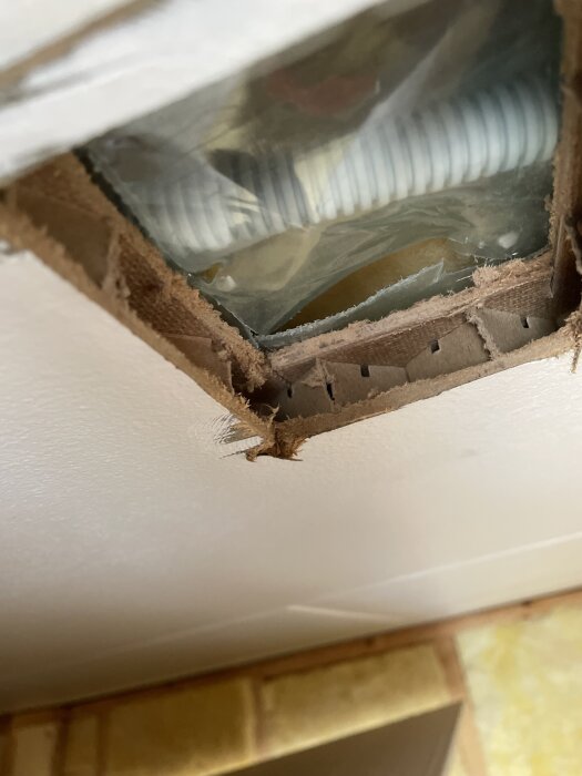 Öppet hål i tak med masonitskiva och plastslang. Ingen synlig regel.