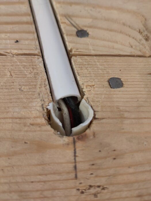 PVC-rör med elkablar i ett träbjälklag, visar kabeldragning inför golvinstallation; kablarna löper individuellt i rören.