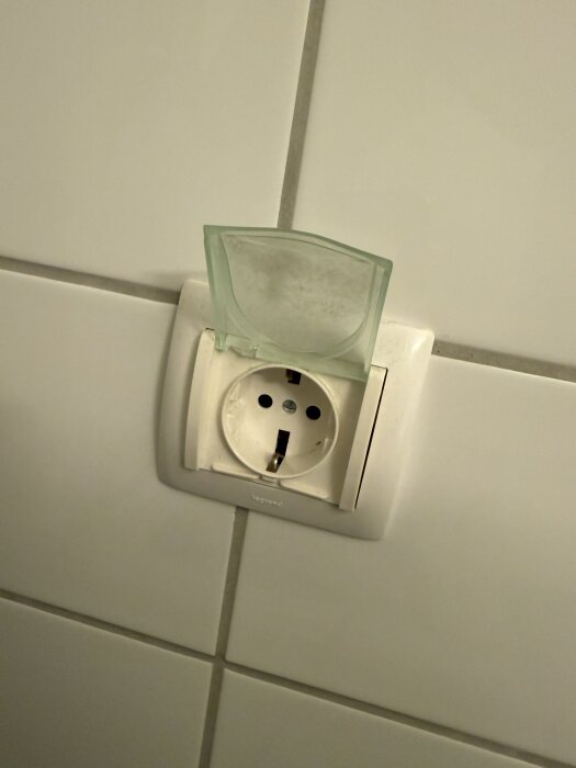 Vägguttag i ett badrum, skyddat av ett transparent lock.