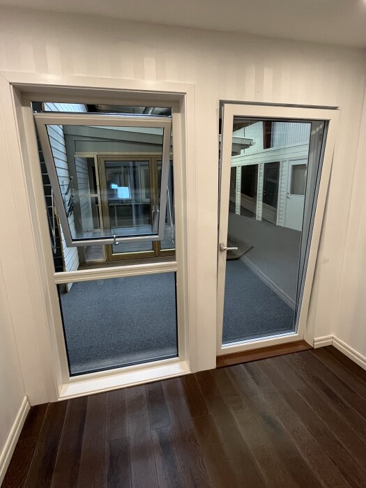 Två moderna fönsterlösningar i ett showroom; ett tvådelat öppningsbart fönster och en altandörr med tilt-funktion, båda stående bredvid varandra.
