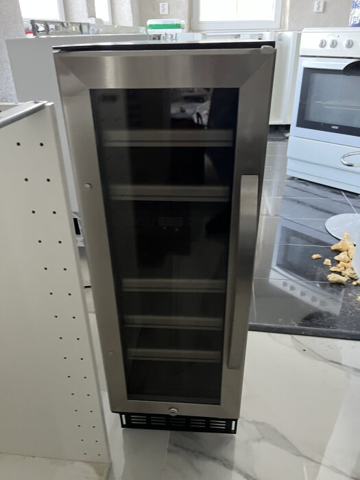 Kylskåp med glasdörr i ett kök; frågeställning om underhåll och eventuell gaspåfyllning.