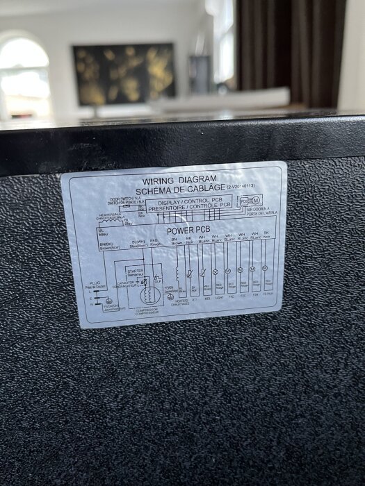 Elektriskt kopplingsschema klistrat på en apparat, visar olika komponenter och kopplingar.