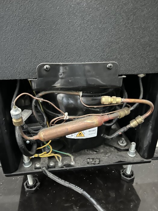 Inre del av en kompressor med rör och kablar, efterfrågan på förslag kring underhåll och möjlig gaspåfyllning.