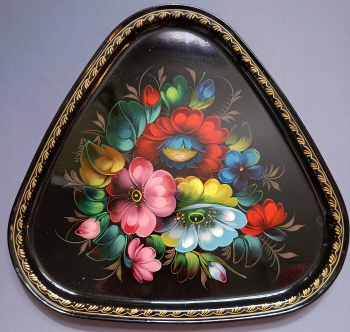 Klassisk zhostovobricka med färgglada blommor och guldfärgat ornament, exempel på rysk folkkonst.