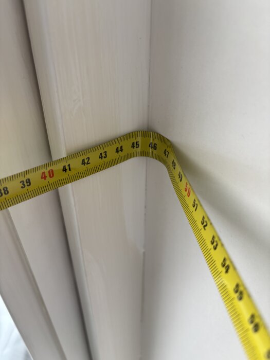 Måttband visar inre hörn av fönsterkarm med markeringar mellan 39 och 59 cm.