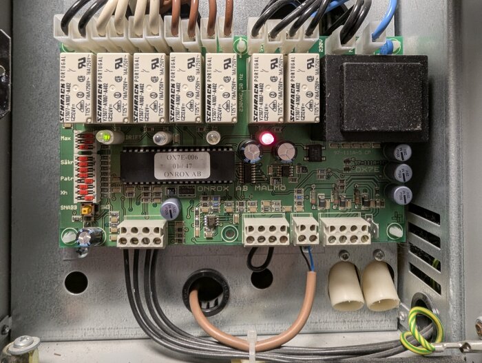 Närbild av kretskort i elpanna med röda LED-dioder som indikerar effektsteg och anslutna kablar för strömförsörjning.