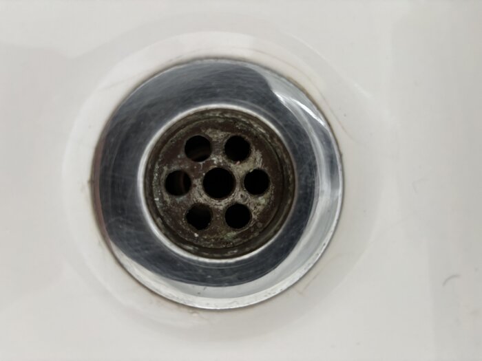 Handfatsbottenventil med rostiga hål i mitten av handfat, svårt att ta bort enligt användare i diskussionstråd om renovering.