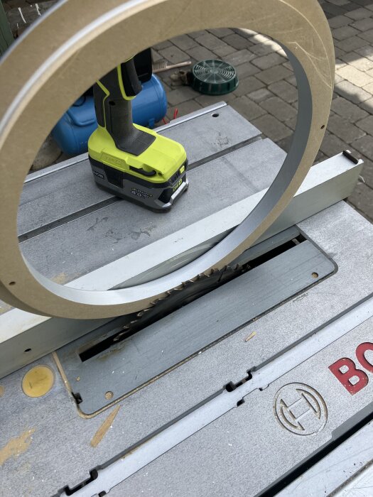 Bordssåg med gul sladdlös fräs och rund MDF-skiva i en byggmiljö.
