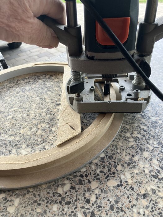 Hand använder fräs för att urholka träbit på ett bord, del av dörr- eller fönsterprojekt.