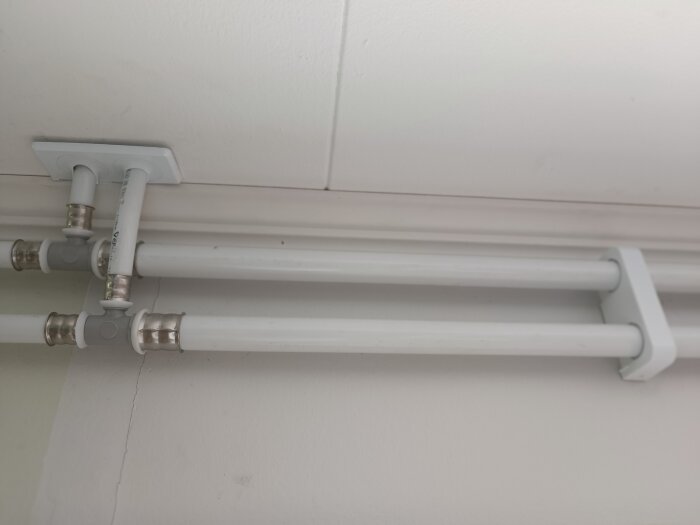 Alupex rörsystem med plastkopplingar och metallfästen monterade i taket, del av diskussion om målning och påverkan av färg på polyeten.