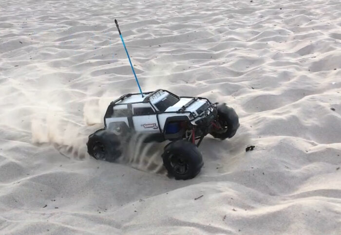Radiostyrd bil av modell Summit som körs snabbt över sanddyner på en strand.