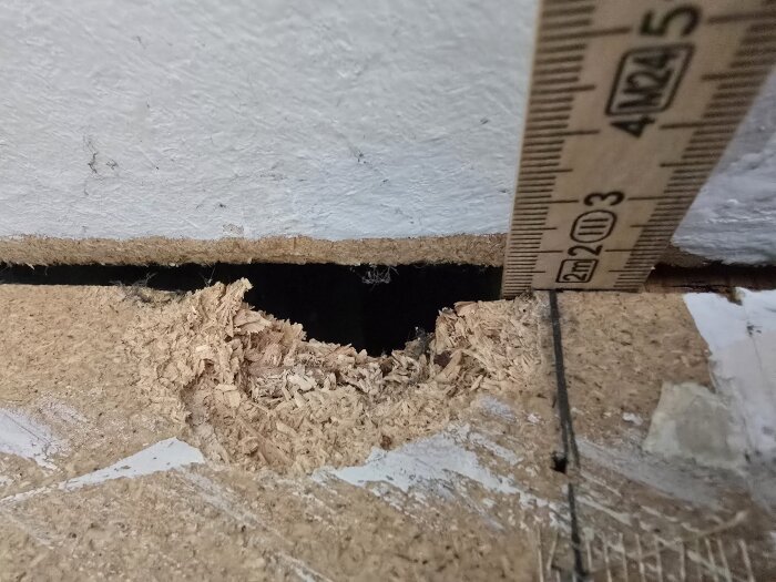 Originaltext: Närbild av ett spånskivematerial med en 2 meter mätstock placerad vid en kant, visar takets materialtjocklek och konstruktionen.