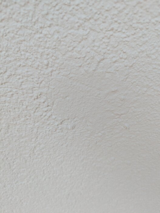 Texturerad vägg med ojämn yta efter husfix; strukturen skiljer sig från originalet men fungerar enligt användaren.