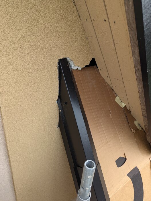 Ett stort hål i husfasaden med skadad frigolitisolering och en del av väggen saknas. En bit kartong syns i bakgrunden.