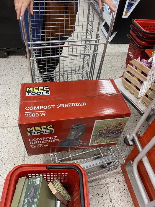 Röd kartong med Meec Tools flistugg/kompostkvarn, 2500 W, placerad i en kundvagn i en butik.
