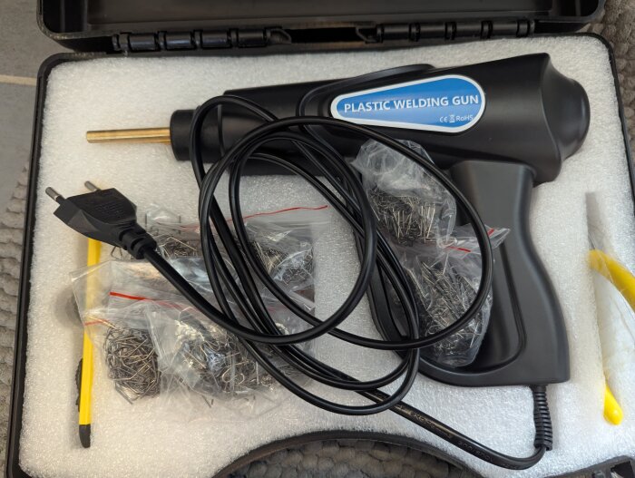 Plastsvetsverktyg med tillbehör i en öppen väska, redo för reparation av en skadad badkarsfront.