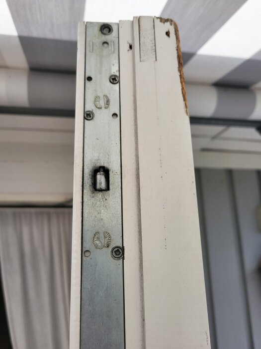 Närbild på sidan av en vit altandörr med synliga beslag och skruvar, tagen i samband med en diskussion om ersättningsbeslag för äldre dörrar.