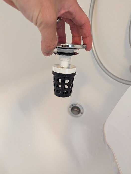 En person håller ett badkarsavlopp med en dold sil över ett badkar.