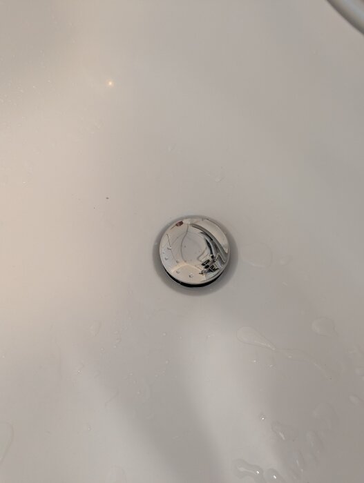 Badrumsavlopp med ny, dold sil installerad i vitt badkar, synlig med vattenstänk runt om.