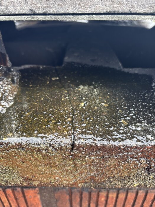 Savupiipun laastiin muodostunut halkeama, kosteutta pinnalla.