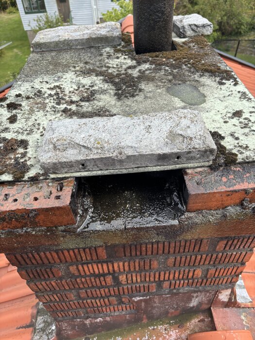 Savupiippu, jossa näkyy halkeama laastissa, ympärillä sammalta ja tiiliverhoilua. Kysymys koskee halkeaman korjausmenetelmää.