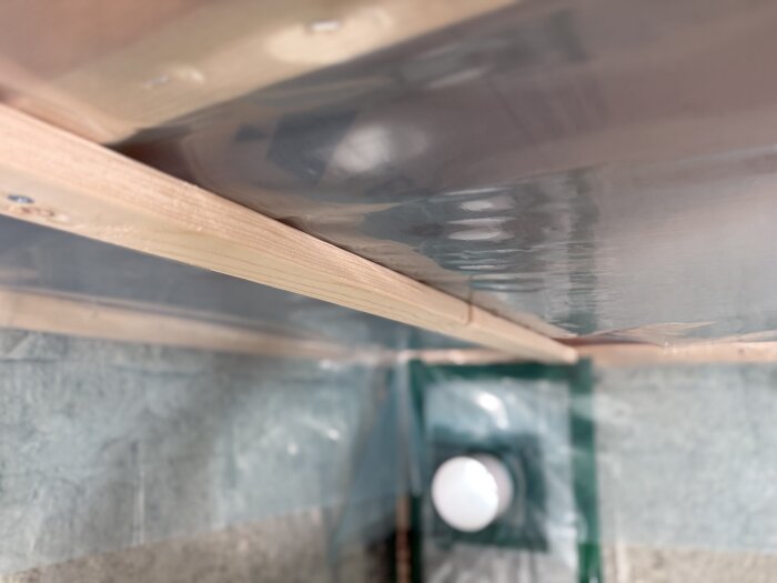 Trätakstöd och plastfolie i byggprojekt, diskussion om trätakregel som stöd nära väggen.