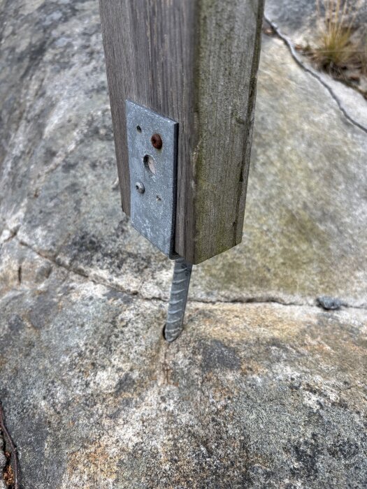 Träfäste monterat på berg med metallplatta och skruv.