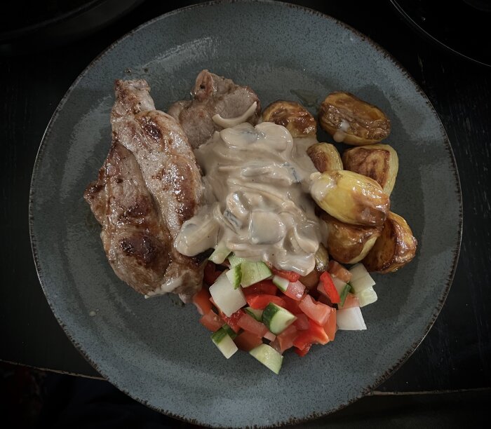 Fläskkarré med ugnsrostad potatis, sallad och en sås av champinjoner och lök.