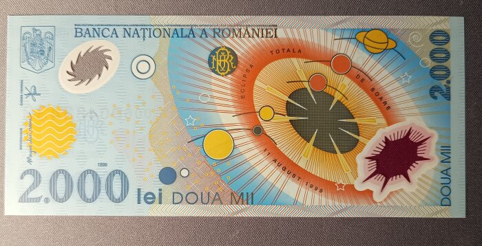 Rumänsk 2000 lei-sedel i polymer med färgglad design från 1999, visande en solförmörkelse och planetmotiv.