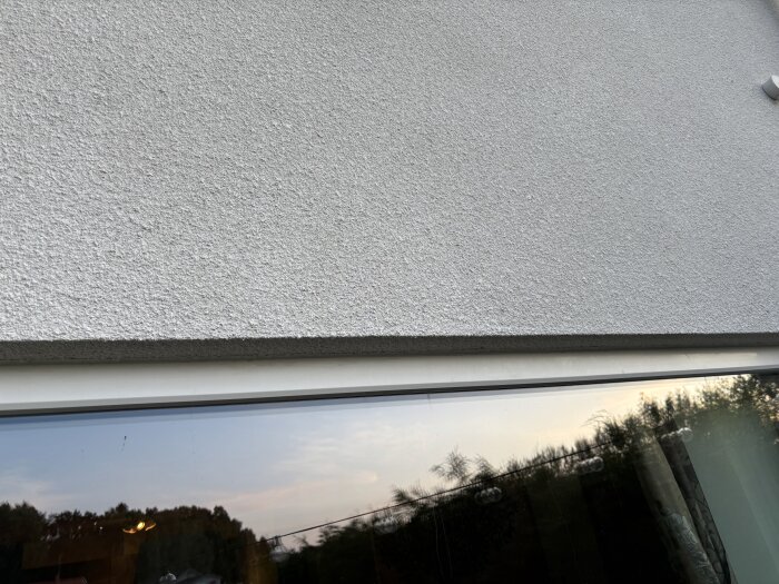 Fönster med svullet foder ovanpå, orsakat av kraftigt regn. Reflektion av omgivning synlig i glaset.