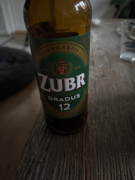 Flaska med tjeckisk öl Zubr Gradus 12 på ett träbord.