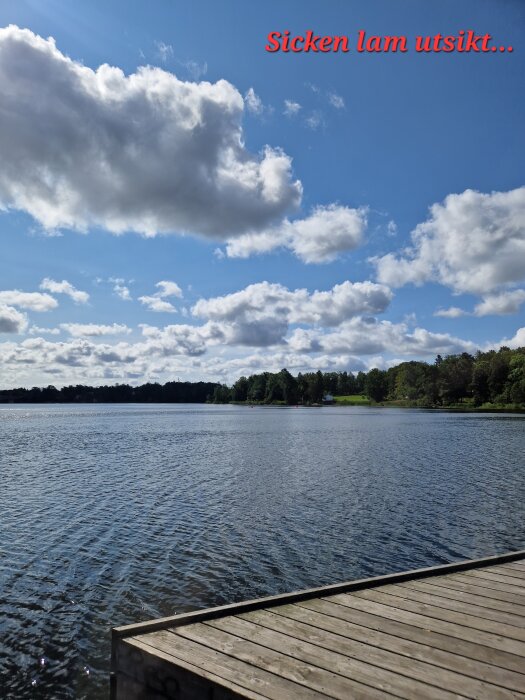Brygga vid en sjö med molnig himmel och skog i bakgrunden, texten "Sicken lam utsikt..." i rött i övre hörnet.