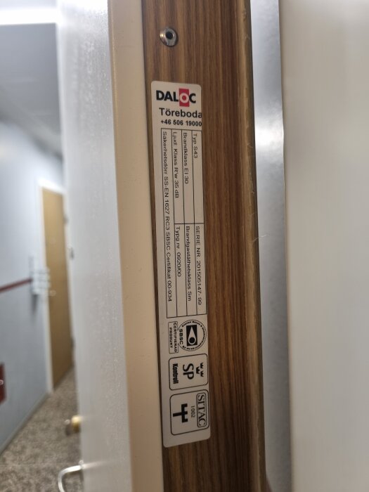 En dörrkarm med en etikett från Daloc som visar specifikationer som typ, klass och säkerhetsinformation.