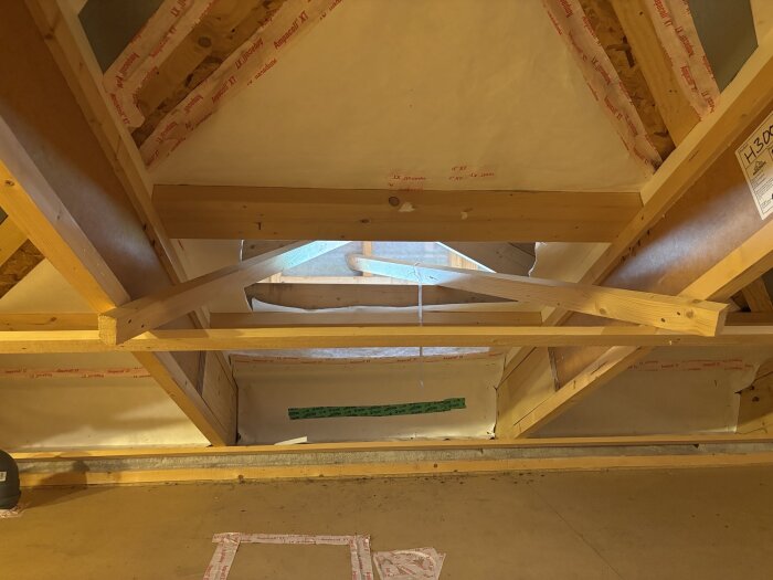 Vind med takbjälkar och isolering, visar en liten utbyggnad eller fack med fokus på ventilation.