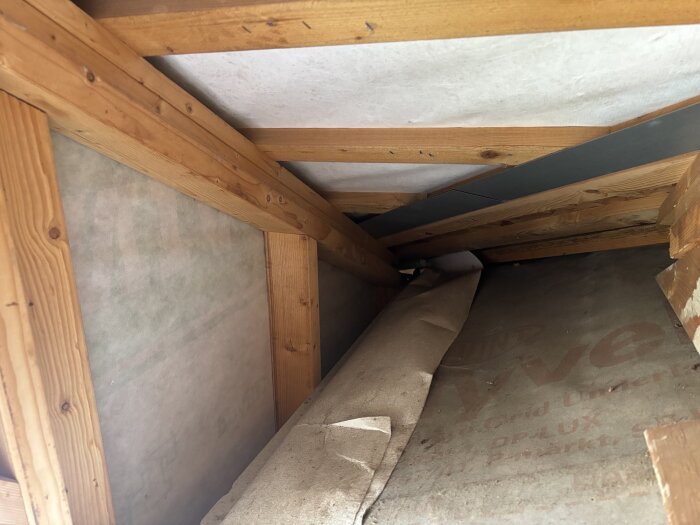 Utbyggnad på kallvind med exponerade takstolar och isoleringsmaterial, visar område med potentiell ventilation och kondensationsproblematik.