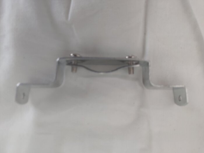 Metallfäste med öppning och skruvar för montering av lampkåpa, fotograferat på vitt underlag.