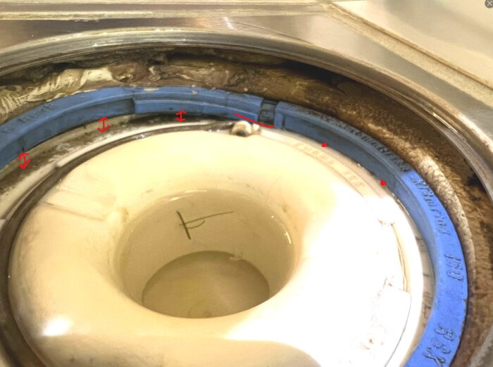 En vit klämring med en blå tätning runt en öppning, där klämringen inte verkar sitta plant hela vägen runt.